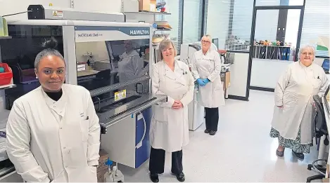  ??  ?? Some members of the virology laboratory team at Ninewells Hospital with the new analyser from South Korea.