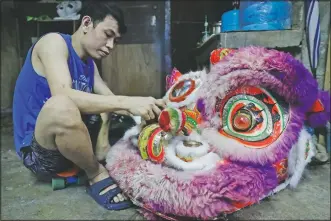  ??  ?? A member of a Dragon and Lion Dance repair a lion’s head as the group seeks other ways to earn a living.