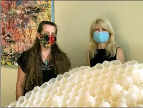  ??  ?? Artist Elizabeth Weber and Justus Fine Art gallery owner Dolores Justus with “Home,” a replica of a wasp nest