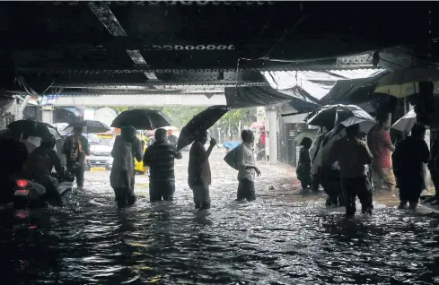  ?? AP ?? People walk through a waterlogge­d street following heavy rains in Mumbai on Tuesday.