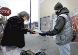  ?? K.C. Alfred San Diego Union-Tribune ?? TOMMY MITCHELL, a volunteer, offers a meal to a woman outside God’s Extended Hand in San Diego. The center has been cited for building code violations.