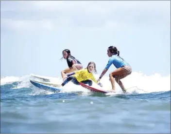  ?? JONO CRAIG photos ?? PHOTO ABOVE: Girls 7-8 shortboard champion Sayler Udell (yellow jersey) catches a wave with Anala Van Pelt (black) and Madison Cambier on Saturday. PHOTO BELOW: Boys 7-9 longboard champion Brixton Craig cross-steps toward the nose of his board.