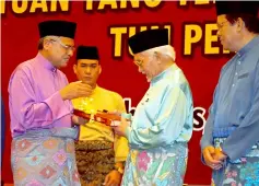  ??  ?? Taib (second right) looks at a book presented to him as a memento by Othman (left).