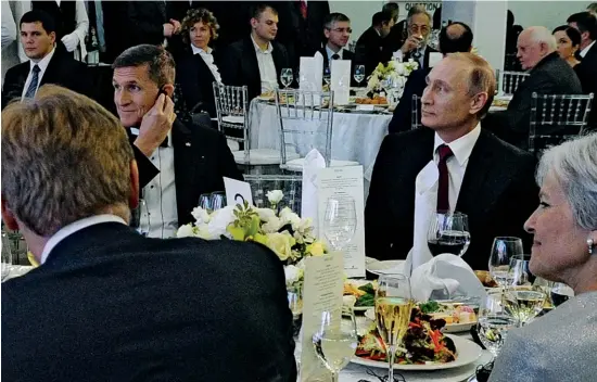  ??  ?? FROM RUSSIA WITH GRUB:
Russian President Putin sits next to retired Army Lieutenant General Flynn at an RT event in 2015. Flynn is at the center of the Trump-russia probe.