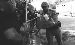  ?? ALLISON DINNER/AFP VIA GETTY IMAGES/TNS ?? A police officer takes flowers from a resident to be placed at a makeshift memorial outside Robb Elementary School in Uvalde, Texas, on May 25, 2022. A teenage gunman killed at least 19 young children and two teachers at the elementary school on May 24.