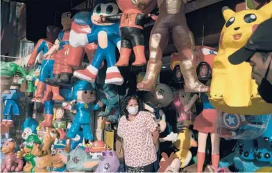  ??  ?? Maricela Ortega stands among an array of piñatas last month at her husband’s shop in Mexico City. The piñata industry, dependent on social gatherings, has seen sales plummet because of the coronaviru­s pandemic.