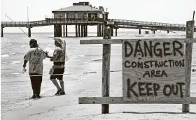 ?? Bob Owen / Staff photograph­er ?? Fishermen stand Wednesday by a warning sign near Bob Hall Pier in Corpus Christi. The pier was damaged during Hurricane Hanna last month.