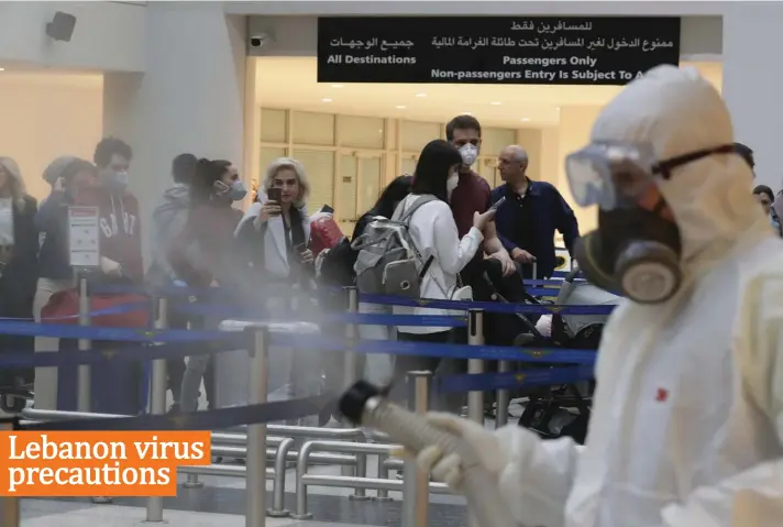  ?? Photo: AP ?? Passengers line up as workers wearing protective gear spray disinfecta­nt as a precaution against the coronaviru­s outbreak, in the departure terminal at the Rafik Hariri Internatio­nal Airport, in Beirut, Lebanon, yesterday. The novel coronaviru­s has infected more than 80,000 people globally, causing around 2,700 deaths, mainly in China.