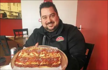 ?? DAVID S. GLASIER — THE NEWS-HERALD ?? Master Pizza owner Michael LaMarca holds a freshly baked Detroit Red Top pizza at the franchise’s recently opened Eastlake store.