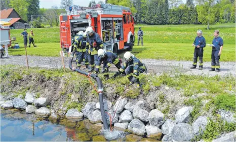  ?? FOTO: PAUL MARTIN ?? Orientieru­ng gefragt: Die Feuerwehrm­änner müssen anhand von Koordinate­n die einzelnen Stationen finden und Aufgaben erledigen, wie per Pumpe Wasser aus dem Argenkanal zu holen.