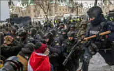  ?? Brett Gundlock/The New York Times ?? Police officers clear the streets of protesters Feb. 19 in Ottawa, Canada. The country’s Conservati­ve Party is courting the truckers who organized the protest and their supporters.