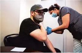  ?? E. JASON WAMBSGANS/CHICAGO TRIBUNE ?? Medical assistant Mary Gomez gives a Moderna COVID-19 vaccine to Tyler Bolte at Central Primary Care Physicians in Portage Park on Friday.