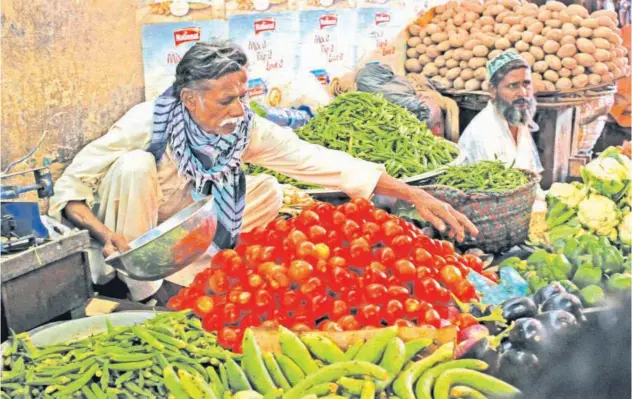  ?? Reuters ?? ↑ Men sell vegetables at their makeshift stalls at the Empress Market in Karachi, Pakistan.