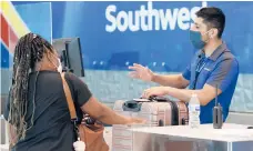  ??  ?? Southwest Airlines employee Oscar Gonzalez, right, assists a passenger June 24 at Love Field in Dallas.
