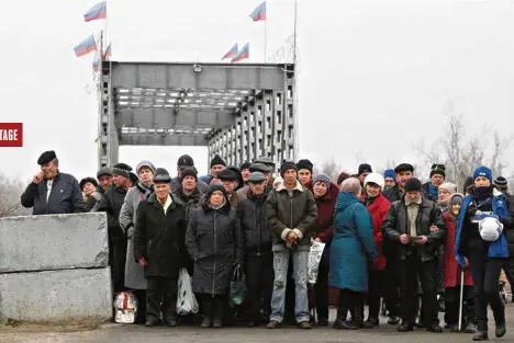  ?? (ALEXANDER ERMOCHENKO/REUTERS) ?? A Stanytsia Louhanska, dans l’est de l’Ukraine, le pont sur le Donets a été dynamité durant le conflit, coupant le passage entre la petite ville ukrainienn­e et Louhansk. Tous les jours, des retraités font la queue pour traverser la ligne de front et aller chercher côté ukrainien la pension à laquelle ils ont droit.