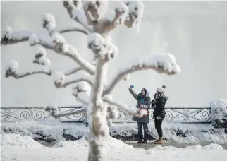  ?? PHOTOS: GEOFF ROBINS/GETTY IMAGES ?? Above and right: Tourists take photos at the Horseshoe Falls in Niagara Falls, Ont., on Jan. 3. The cold snap which has gripped much of Canada and the United States has nearly frozen over the American side of the falls.