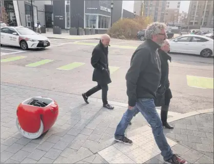  ?? Matt O’brien / Associated Press ?? Piaggio Fast Forward CEO Greg Lynn, center, is followed by one of his company’s Gita robot in Boston. The two-wheeled machine, which is carrying a backpack, uses cameras and sensors to track its owner.