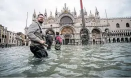  ?? FILIPPO MONTEFORTE/GETTY-AFP ?? People walk across the flooded St. Mark’s Square on Friday in Venice, Italy.