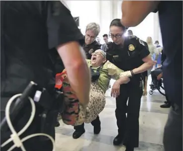  ?? Jacquelyn Martin Associated Press ?? DEMONSTRAT­ORS protesting proposed Medicaid cuts are removed from a sit-in outside Senate Majority Leader Mitch McConnell’s office. President Trump made a campaign promise not to reduce Medicaid.