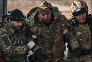  ?? (AP/Libkos) ?? Medics help a soldier who was wounded in a battle get to an evacuation vehicle Wednesday near Bakhmut in Ukraine’s Donetsk region.