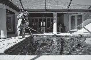  ?? ?? John Brouse removes leaves from the pool at his home in the Wind Gate Ranch community on the far West Side. Brouse built his home in 2006 and has seen a lot of growth in the area.