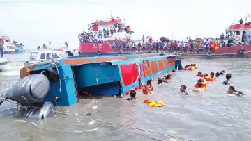  ?? — AFP photo ?? Members of an Indonesian search and rescue team try to help passengers from a capsized boat in Tarakan.