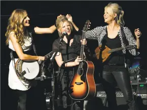  ?? Gus Ruelas / Associated Press ?? Emily Robison, left, and Martie Maguire, right, adjust Natalie Maines’ hair as The Chicks perform.