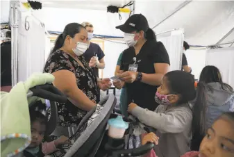  ?? Lea Suzuki / The Chronicle ?? Nurse Angelica Juarez (right) provides vaccinatio­n informatio­n to Gladys Sonchonche­x and her children at the Southeast Health Center vaccinatio­n tent Thursday in San Francisco.