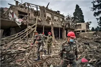  ?? ISMAIL COSKUN/ IHA VIA AP ?? On Oct. 11, Azerbaijan­i soldiers and firefighte­rs search for survivors after rocket fire overnight by Armenian forces in a residentia­l area in Ganja, Azerbaijan’s secondlarg­est city, near the border with Armenia.