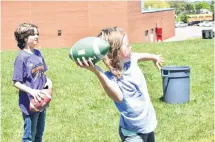  ??  ?? Mollie Cleary unleashes a pass while Sam Wagner waits for his turn at a football camp held June 13 at A.G. Baillie Memorial School in New Glasgow.