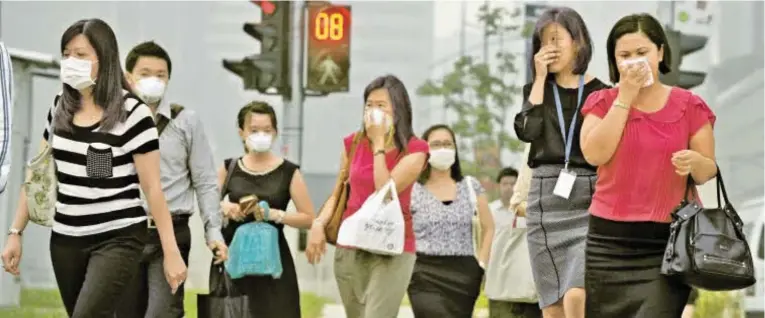  ?? Bild: SN/AP ?? Den Bewohnern Singapurs bleibt die Luft weg. Die Regierung rät, auf Aktivitäte­n im Freien zu verzichten. Im Bild Angestellt­e auf demWeg nach Hause.