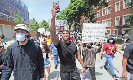  ?? MIKE DE SISTI/MILWAUKEE JOURNAL SENTINEL ?? Milwaukee Bucks player Sterling Brown, center, takes a selfie as he walks down North Astor Street with Milwaukee Bucks player Robin Lopez, left, during a march in Milwaukee on Sunday.