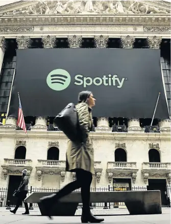  ?? Picture: REUTERS ?? STEADY AS SHE GOES: Pedestrian­s walk past a banner with the Spotify logo as the company lists its stock on the New York Stock Exchange with a direct listing in New York