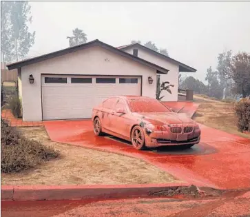  ?? Marcus Yam Los Angeles Times ?? A LAKE ELSINORE property is coated with fire retardant after an air drop last week. Some fire experts have criticized Gov. Jerry Brown’s characteri­zation of rampant wildfires as the state’s “new normal.”