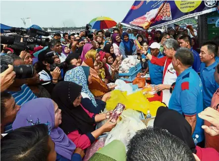  ?? — Bernama ?? The people’s sales: Dr Ahmad Zahid helping to ‘sell’ frozen meat during his visit to a Jualan Sentuhan Rakyat programme held at Sekolah Menengah Sains Bagan Datuk.