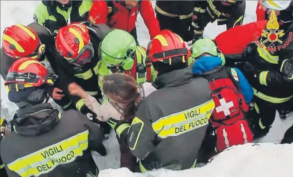  ?? DEPARTAMEN­TO DE BOMBEROS DE ITALIA / EFE ?? Los bomberos rescatan a una de las supervivie­ntes por un agujero abierto en la nieve que entierra el hotel sepultado por el alud