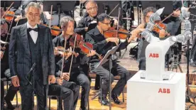  ??  ?? Der blinde Tenor Andrea Bocelli (vorne links) sang unter der Leitung von „Yumi“(vorne rechts).