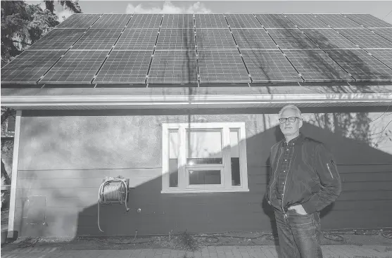  ?? QC PHOTO BY MICHAEL BELL ?? Stephen Hall stands in front of solar panels mounted to the roof his home studio.