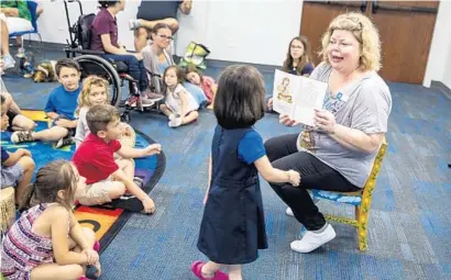  ?? PATRICK CONNOLLY/ORLANDO SENTINEL ?? Youth services librarian Crystal Hamrick reads the first chapter of “Charlotte’s Web” to children during a One Book, One Community event Wednesday at the Veterans Memorial St. Cloud Library.