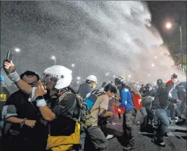  ?? Sakchai Lalit The Associated Press ?? Police use water cannons to disperse pro-democracy protesters during a street march Sunday in Bangkok, Thailand. The ongoing protests seek Prime Minister Prayuth Chan-ocha’s resignatio­n and other political reforms.