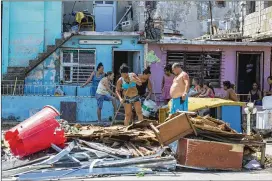  ?? PHOTOS BY DESMOND BOYLAN / ASSOCIATED PRESS ?? People clear debris outside their homes after the passing of Hurricane Irma in Havana on Monday. Cuban state media reported 10 deaths despite the country’s usually rigorous disaster preparatio­ns.