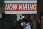  ?? JEFF CHIU — THE ASSOCIATED PRESS FILE ?? A man wearing a mask walks under a “Now Hiring” sign at a CVS Pharmacy in San Francisco.