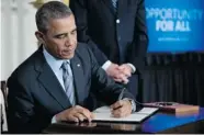  ?? CAROLYN KASTER/ THE ASSOCIATED PRESS ?? U.S. President Barack Obama signs a memo directing the federal government not to discrimina­te in its own hiring.