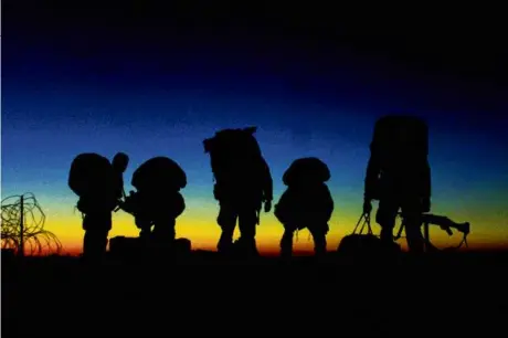  ?? RICK LOOMIS/LA TIMES-POOL/AFP VIA GETTY IMAGES ?? US Marines geared up in front of a sunset before loading into a transport vehicle at Afghanista­n’s Kandahar Internatio­nal Airport, Dec. 19, 2001.