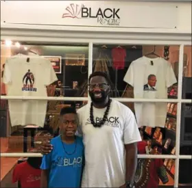  ?? GARY PULEO — DIGITAL FIRST MEDIA ?? Owner Anwar Muhammad smiles at The Black Reserve Bookstore in Lansdale with his son Anwar Muhammad, who can often be found at the store greeting customers with his dad.