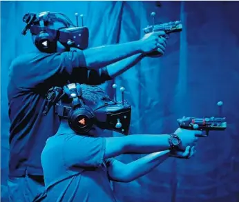  ?? Photograph­s by Luis Sinco Los Angeles Times ?? KNOTT’S BERRY FARM visitors Derek Phelps and his brother Tyrus, 8, play a round of VR Showdown in Ghost Town. Attraction­s that include a gaming element are increasing­ly popular at area theme parks.