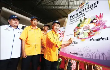  ??  ?? Ahmad signs the ‘ Sarawak Fama Festival 2019’ billboard at Medan Niaga Satok. — Photo by Muhammad Rais Sanusi.