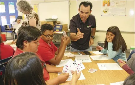  ?? PHOTO ?? Agustin Vasquez (second from right), ECESD after school education and safety program tutor, explains a game challege on National Pi Day at De Anza Magnet School in El Centro on Tuesday. WILLIAM ROLLER