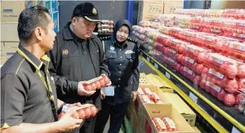  ?? — Bernama photo ?? KPDNHEP Kuala Lumpur director Ariffin Samsudin (centre) inspects the eggs sold at a supermarke­t in Setiawangs­a.