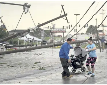  ??  ?? Aftermath: Residents carrying a stroller over downed power lines after a tornado tore through Jefferson City, Missouri. — AP
